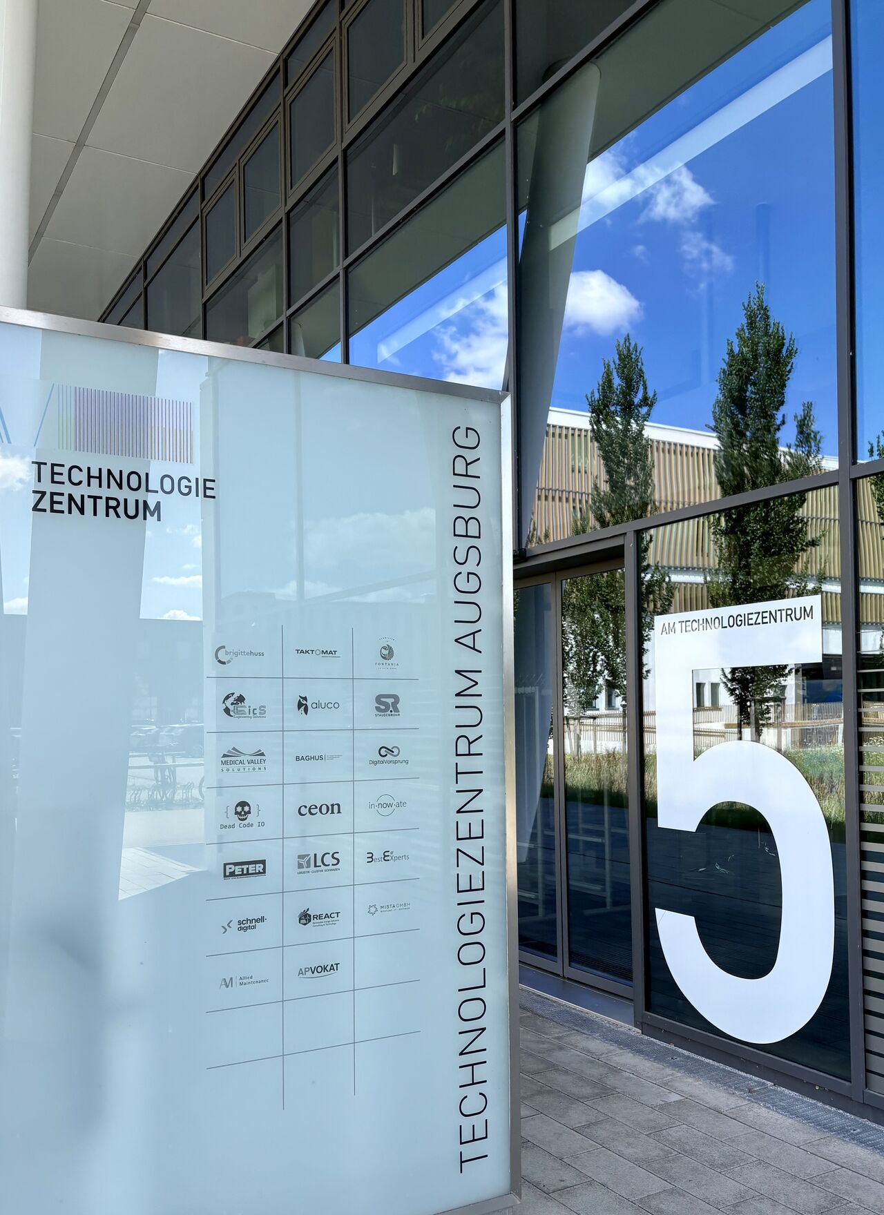 Entrance area of the Augsburg Technology Center with the REACT company sign